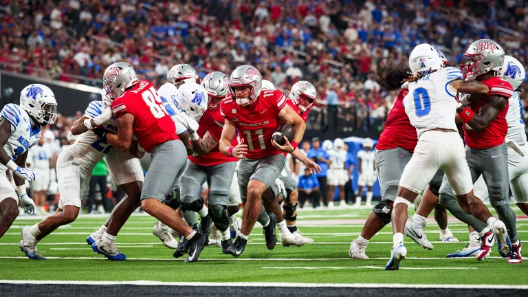 Jackson Arnold carrying the ball behind UNLV blockers against Memphis in August 2026